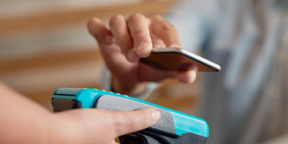 Close-up of a person making a contactless payment with a smartphone over a card reader. 